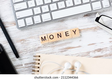 Money Concept With Letters On Cubes. Still Life Of Office Workplace With Supplies. Flat Lay Vintage Wooden Desk With Computer Keyboard, Headphones, And Notebook. Investment Strategy And Economy