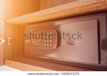 Money and documents in an open digital safe on a closet shelf. The safe has a keypad and a screen for security and protection. The safe can be locked and unlocked with a code and a password.