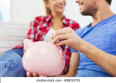 Money, Finance, Investment, Saving And People Concept - Close Up Of Happy Couple Putting Euro Coin To Piggybank