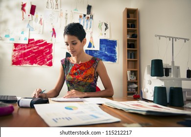 Money And Financial Planning, Young Hispanic Self-employed Woman Checking Bills And Doing Budget With Calculator, Computer And Papers In Fashion Design Studio