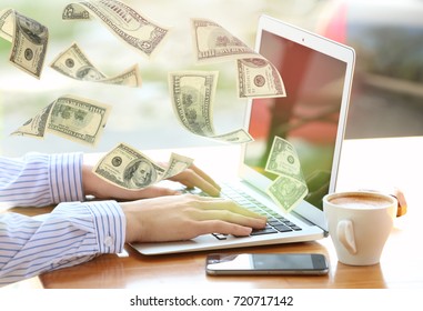 Money flying out of laptop while woman using it at table in office