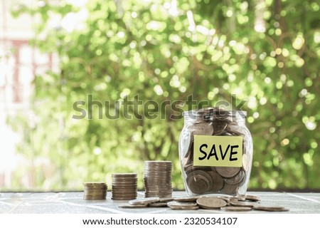 Money in glass jar and coin stack word save paper note.
Concept save money by managing their finances properly