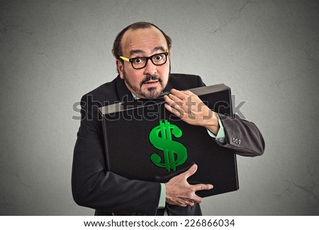 Money greed. Business man holding holding case with dollars tightly isolated on grey wall background. Worship, miser, excessive gain, finance concept 
