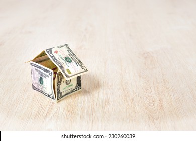 Money house made of dollar bills on wooden background