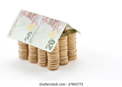 Money house made from stack of coins and Turkish lira banknote roof - isolated with reflection
