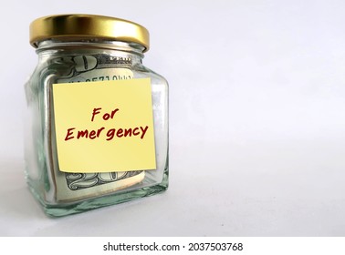 Money Jar Bottle On Copy Space White Background With Yellow Stick Note Written FOR EMERGENCY, Means To Save Cash To Use In Crisis Unexpected Life Crisis By Buiding Emergency Fund