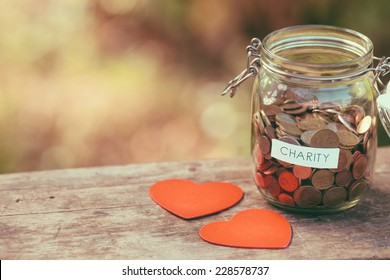 Money jar full of coins for charity and a couple of heart shapes