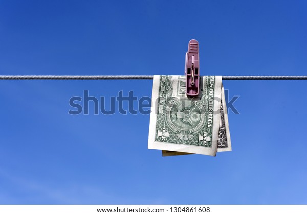 Money laundering of a one US Dollar bill note from\
the USA on a washing line with blue sky for AML Anti laundering\
finance business crime\
ideas