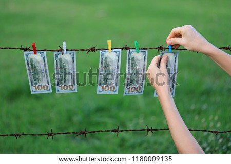 Money Laundering. Money Laundering US Dollars Hung Out To Dry. 100 Dollar Bills Hanging On Rusty Barbed Wire