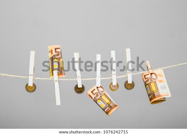 Money laundry scandal concept.\
Euro money hanging on a string fastened with white\
clothespins.