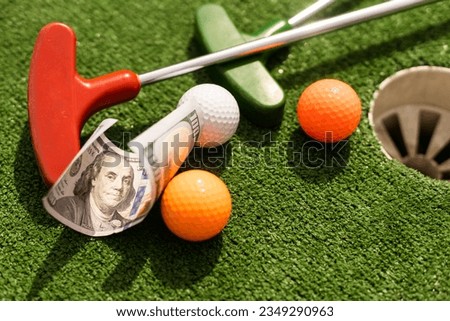 Money, mini golf balls on grass. Concept of sports bet