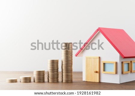Money and miniature house. Finance and investment. Miniature house and stack of coins on wood table.
