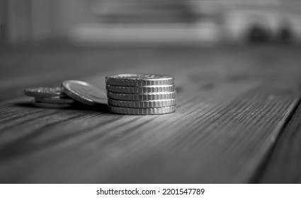 Money On The Table. Coins Are Stacked On The Table. Black And White Photo Of Coins Shooting From The Side.