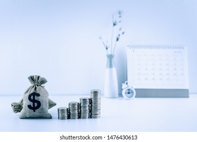Money planning and rich habits, financial concept : US dollar bags, stacks of rising coins, a clock, a calender on a table, depicts value of assets increase over time on higher interest and inflation