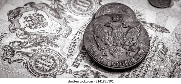 Money of Russian Empire, old coins and banknote. Antique copper and paper currency with Imperial coat of arms of Russia. Concept of vintage texture, rare history. Black and white panoramic photo.