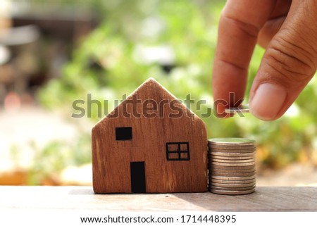 money saving concept image of stack coins and house model ,hand holding coins 