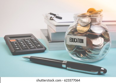 Money Saving For Education Fee Or School Free In The Glass Bottle With Book And Pen On Blue Background In Pastel Color Effect. Money Saving Concept.