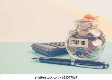 Money Saving For Education Fee Or School Free In The Glass Bottle With Pen On Blue Background In Pastel Color Effect. Money Saving Concept.