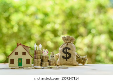 Money saving, first time asset / property buyer concept : Family couple, home model, piggy bank, dollar and tax bags, stacks of rising coins, depict budget planning for basic needs, personal expense.