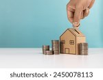 Money saving,real estate investment, investing for home lone. Hand putting coin to house money box for saving money to buy a house