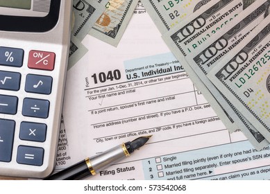 money, tax form, calculator and pen on desk.