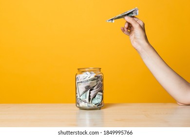 Money Transfers, Deposits To A Foreign Currency Account. Hand With An Airplane From A Banknote Near A Bank With Money, Yellow Background