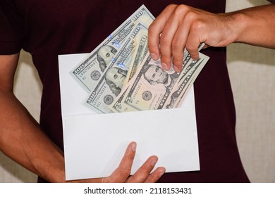 Money in a white envelope in the hands of a man. Dollars, a wad of dollars.