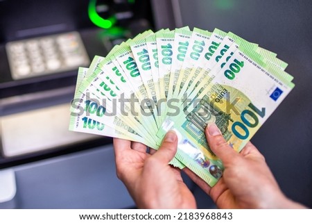 A lot of money in a woman's hand. Euro banknotes and cash machine in background. Money in hands. 