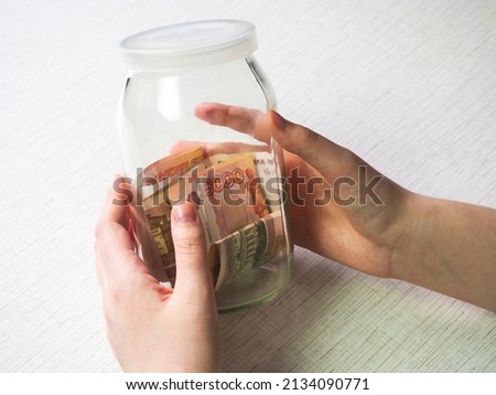 A Moneybox of money in hand .  The concept of savings, piggy bank, last money. Money, finance, the concept of budget, savings. Business growth. Accounting, paying taxes. Financial concept.