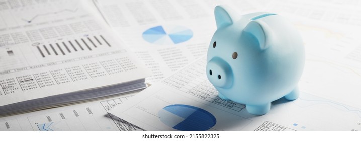 Moneybox for money on the background of documents and financial charts. Investment and capital accumulation concept. - Shutterstock ID 2155822325