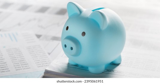 Moneybox for money on the background of documents and financial charts. Investment and capital accumulation concept - Shutterstock ID 2395061951