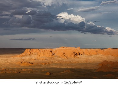 Mongolia Gobi desert, general view of Bayanzag Flaming Cliffs at golden hour under stormy sky