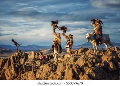 Mongolian Eagle Hunters In Traditionally Wearing Typical Mongolian Fox Dress Culture Of Mongolia On Altai Mountain Background At Ba-yan UiGII, MONGOLIA