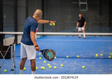 Monitor teaching padel class to man, his student - Trainer teaches boy how to play padel on indoor tennis court