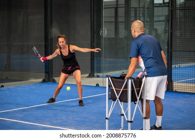 Monitor teaching padel class to woman, his student - Trainer teaches young girl how to play padel on indoor tennis court - Powered by Shutterstock