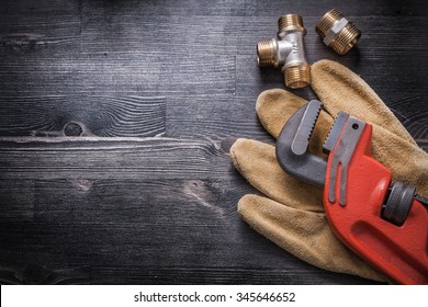 Monkey wrench brass plumbing fittings leather safety gloves construction concept.