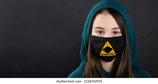 MONKEYPOX. Teenage Girl In A Medical Mask. A Sign With A Danger Sign And A Monkey On The Mask. Virus, Epidemic, Disease.Black Background.