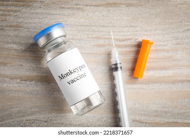 Monkeypox Vaccine In Glass Vial And Syringe On Wooden Table, Flat Lay