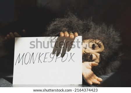 Monkeypox virus concept. Monkey toy holding sign with word MONKEYPOX.