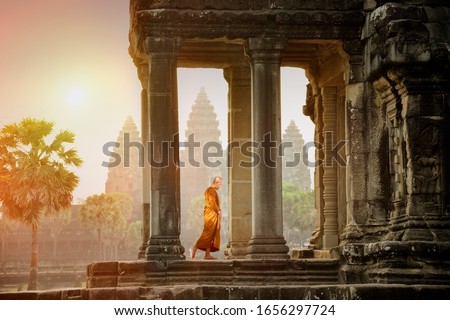 Monks walk on the balcony to see the stone carving at sunset of Angkor Wat.