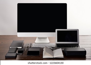 monoblock computer with various gadgets on wooden table isolated on grey