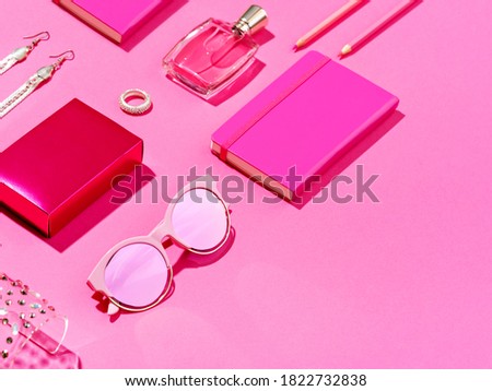 Monochromatic minimalist set of feminine accessories. High angle view of pink notepad, pencils, perfume flask and shiny jewellery. Femininity concept. Copy space