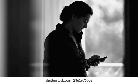 Monochromatic scene of woman using smartphone device browsing internet on cellphone, person staring at screen