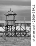 Monochromatic view of a traditional Mongolian watchtower overlooking a vast grassland under a dramatic sky.