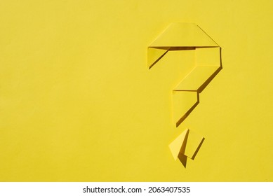 Monochromatic yellow background of a folded paper origami question mark with copy space as a template for conceptual themes