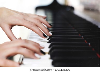 Monochrome black and white manicure nails on piano keys, female graceful hands playing music close up