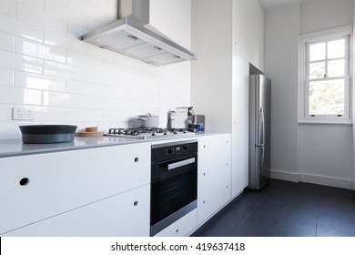 Monochrome Clean White Kitchen Bench Top And Cupboards With Appliances