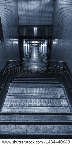 Monochrome Cyanotype picture of a subway/tube station entrance in a dystopian futuristic metropolis city which is reachable by a couple of stairs.