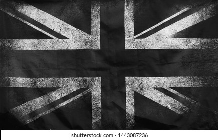 a monochrome full frame image of an old stained dirty union jack british flag with dark crumpled edges