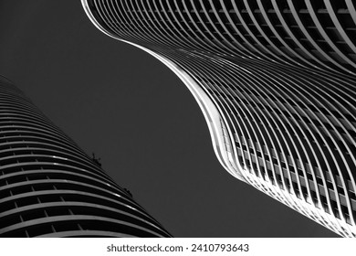 Monochrome image of contrasting skyscrapers, featuring fluid architecture against a dark sky. - Powered by Shutterstock